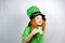 Saint Patricks Day holiday. Cute smiling small girl with decorative red beard in green dress and leprechaun\\\'s hat