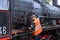 Saint Petersburg, Russia-August 24, 2021: Steam locomotive driver checks steam engine before shipment