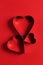 Saint Valentine day minimalistic greeting card, heart-shaped cookie cutters on red background with beautiful shadows