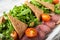 Salad from arugula and tomatoes. Slices of chopped bread and sliced meat. Close-up on a white plate