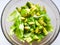 Salad with avocado and sesame seeds, oil is poured, on a wooden. Avocado salad in a plate, vegetarian food, green dietary salad