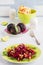 Salad with baked beets, arugula, raisins and walnuts on a green plate on the table in kitchen. Whole beetroots, lime, fresh bread