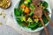 Salad with a baked pumpkin, chard, broccoli, and pumpkin seeds in ceramic plate on stone or concrete background table background.