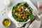 Salad with a baked pumpkin, chard, broccoli, and pumpkin seeds in ceramic plate on stone or concrete background table background.