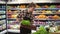 Salad bar with organic vegetables and greens in supermarket. Male shop employee arranging fresh greens on a bar in local