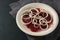 Salad from beetroot slices and onion rings on a white plate and a dark slate background, copy space, selected focus