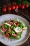 Salad with burrata, parma and cherry tomatoes confit. Spoon and a fork on the grey background