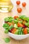 Salad and cherry tomatoes in a bowl, olive oil in the background