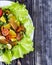 Salad with fish and vegetables on a white plate decorated with tomatoes, herbs and sweet peppers home kitchen