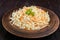 Salad of fresh cabbage and carrots in a clay bowl on dark wooden background