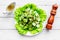 Salad with fresh cucumbers and lettuce near paperbox and gravy boat. Grey wooden background top view