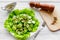 Salad with fresh cucumbers and lettuce near paperbox and gravy boat. Grey wooden background top view