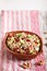 Salad of germinated buckwheat, avocado, walnut and pomegranate seeds in clay plate on white wooden background