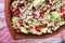 Salad of germinated buckwheat, avocado, walnut and pomegranate seeds in clay plate on white wooden background