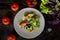 Salad with meat, lettuce, tomatoes, peppers, basil, olive oil on a gray plate on a dark wooden table. Garnished with