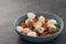 Salad with mozxarella, tomatoes and arugula in a blue bowl on concrete background