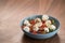 Salad with mozxarella, tomatoes and arugula in a blue bowl on walnut wood table