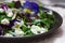 Salad of pansies and herbs seasoned with vegetable oil, lemon juice and spices