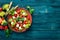 Salad in a plate. Feta cheese, cherry tomatoes, paprika, lettuce. Healthy food. On a blue wooden table table.