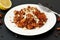 Salad with red quinoa,apple and carrot with almond on white plate on black background