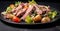 Salad with roast beef, potatoes and vegetables on a black plate