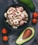 Salad with shrimp, avocado and tomato sauce in a black dish.