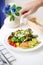 Salad. Smoked salmon and avocado salad with hand pouring salad dressing on the background. Selective focus on the smoked salmon