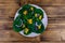 Salad with spinach leaves, pieces of orange, sesame seeds and onion in a ceramic plate. Top view