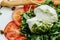 Salad with traditional italian burrata cheese with arugula, tomatoes and green pesto, Food recipe background. Close up