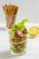 Salad in transparent glass tomatoes cucumbers snacks croutons lettuce. Crispas and lemon in the background. salad dressing with