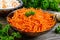 Salads from fresh carrots. Korean spicy vegetables salad in bowl on a wooden table.