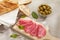 salami fine slices with bread and olives. sausage and herbs on a wooden board. snack on a light table.