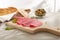 salami fine slices with bread and olives. sausage and herbs on a wooden board. snack on a light table.
