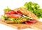 Salami sandwich with full-corn bread on cutting board on white
