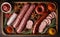 salami sausages, spices and meat products in a wooden tray, Free space for text,