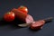 Salami, tomatoes and a sharp dangerous knife on a dark background. Concept and metaphor for male circumcision and male cosmetic