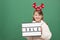 Sale, Christmas and New Year shopping. Cute little caucasian girl with Christmas reindeer antlers and holding a sale sign in her