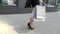 Sale, consumerism: Confident lady with shopping bags walking in a city. Female legs in high heels shoes walking in the