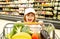 Sale, consumerism and people concept - excited kids with food in shopping cart at grocery store.