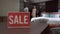 Sale message on table in furniture store with blurred buyer and seller talking discussing furnishings comfort and