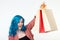 Sale, shopaholic and consumer concept - beautiful girl with blue hair standing with shopping bags on white background