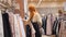 Sale - woman in dress store chooses a clothes - shopping concept