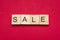 Sale word on scrabble wooden tiles on red background