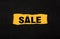 Sale words in ripped black paper with yellow background