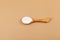 Salep flour in wooden spoon. Also spelled sahlep or sahlab. Salep flour is consumed in beverages and desserts. Beige background,