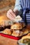 Sales Assistant In Bakery Putting Contains Nuts Label Into Stack Of Freshly Baked Cinnamon Buns