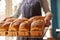 Sales Assistant In Bakery With Tray Of Freshly Baked Organic Sourdough Bread Loaves