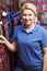 Sales Assistant In Pet Store With Display Of Dog Leashes