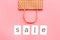 Sales message. Text Sale near paper shopping bag on pink background top-down copy space
