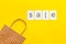 Sales message. Text Sale near paper shopping bag on yellow background top-down copy space